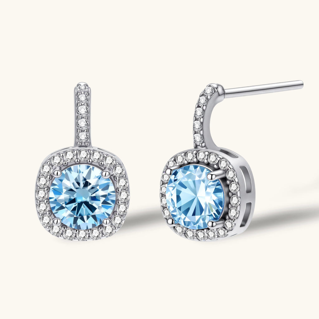 Sterling silver drop earrings featuring cushion-cut blue moissanite stones surrounded by sparkling halo settings