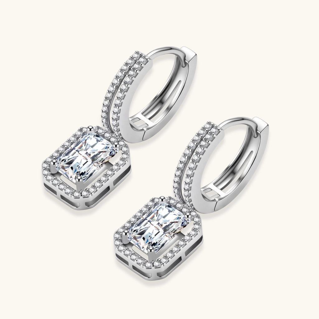 Sterling silver huggie hoops with emerald-cut moissanite drops featuring pavé-set crystals on white background.