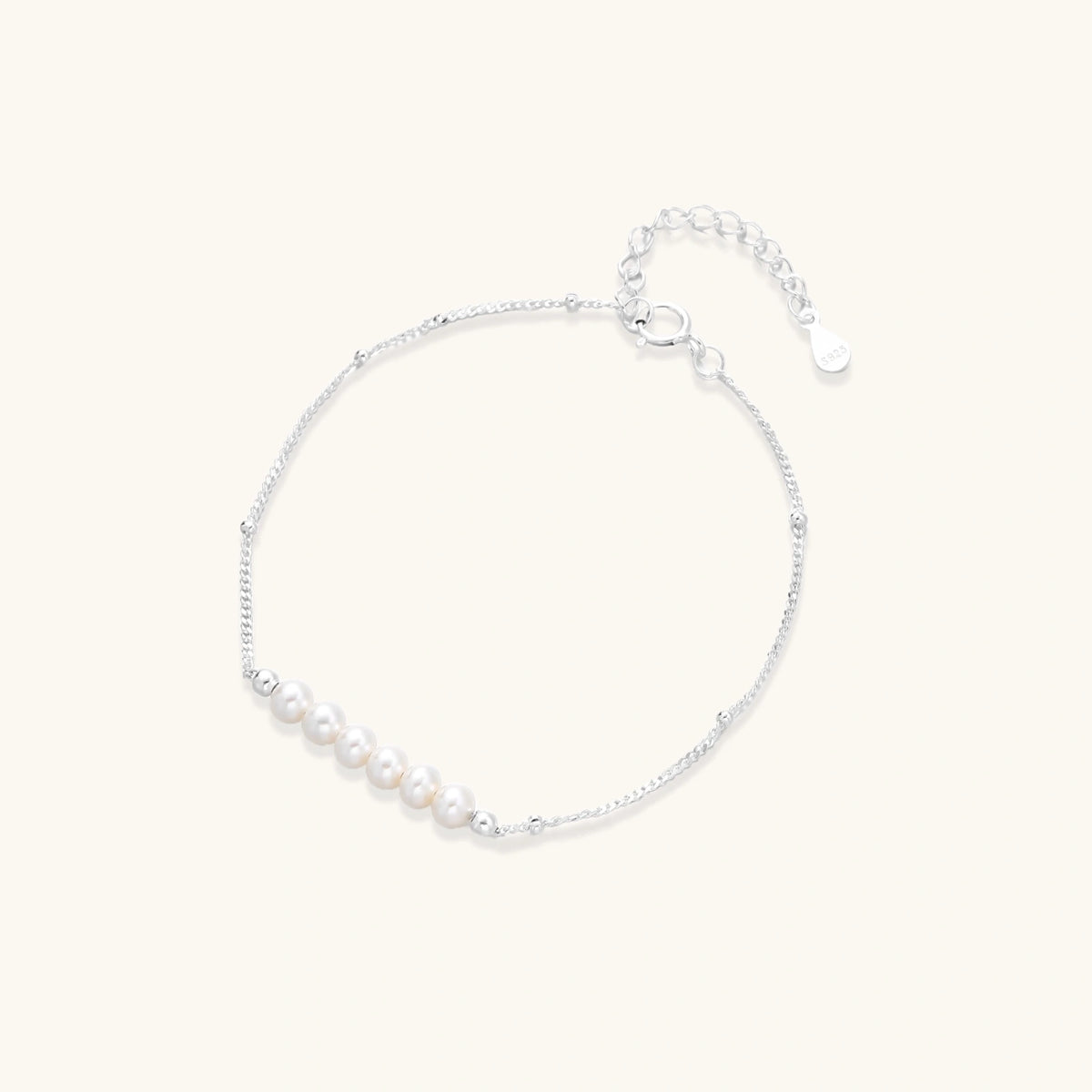 Delicate rhodium-plated silver chain bracelet with row of small baroque pearls centered on white background.