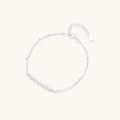 Delicate rhodium-plated silver chain bracelet with row of small baroque pearls centered on white background.