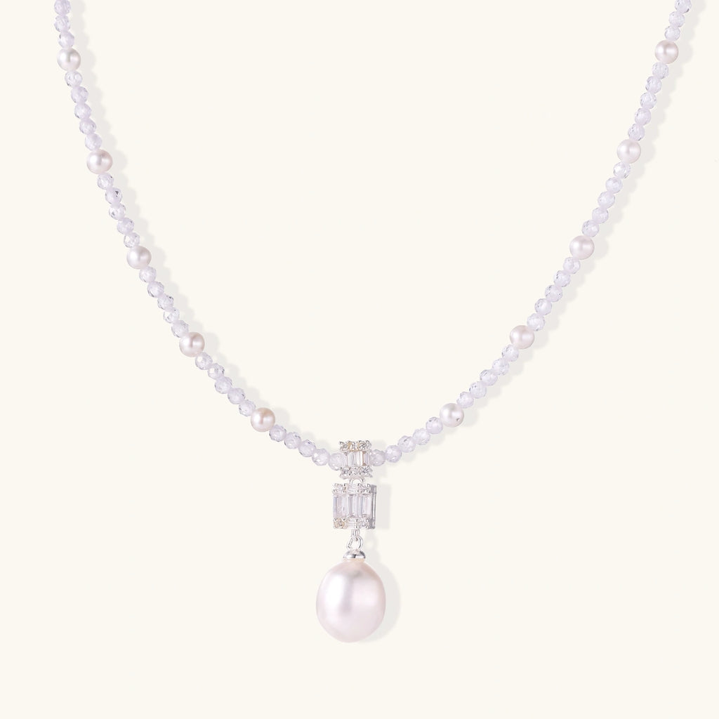 Dainty necklace with lavender crystal beads, freshwater pearls, geometric pendant, and large pearl drop on white background.