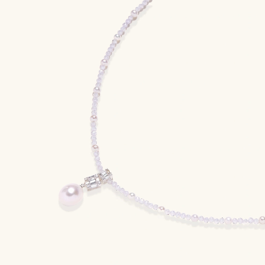 Dainty necklace with lavender crystal beads, freshwater pearls, geometric pendant, and large pearl drop on white background.