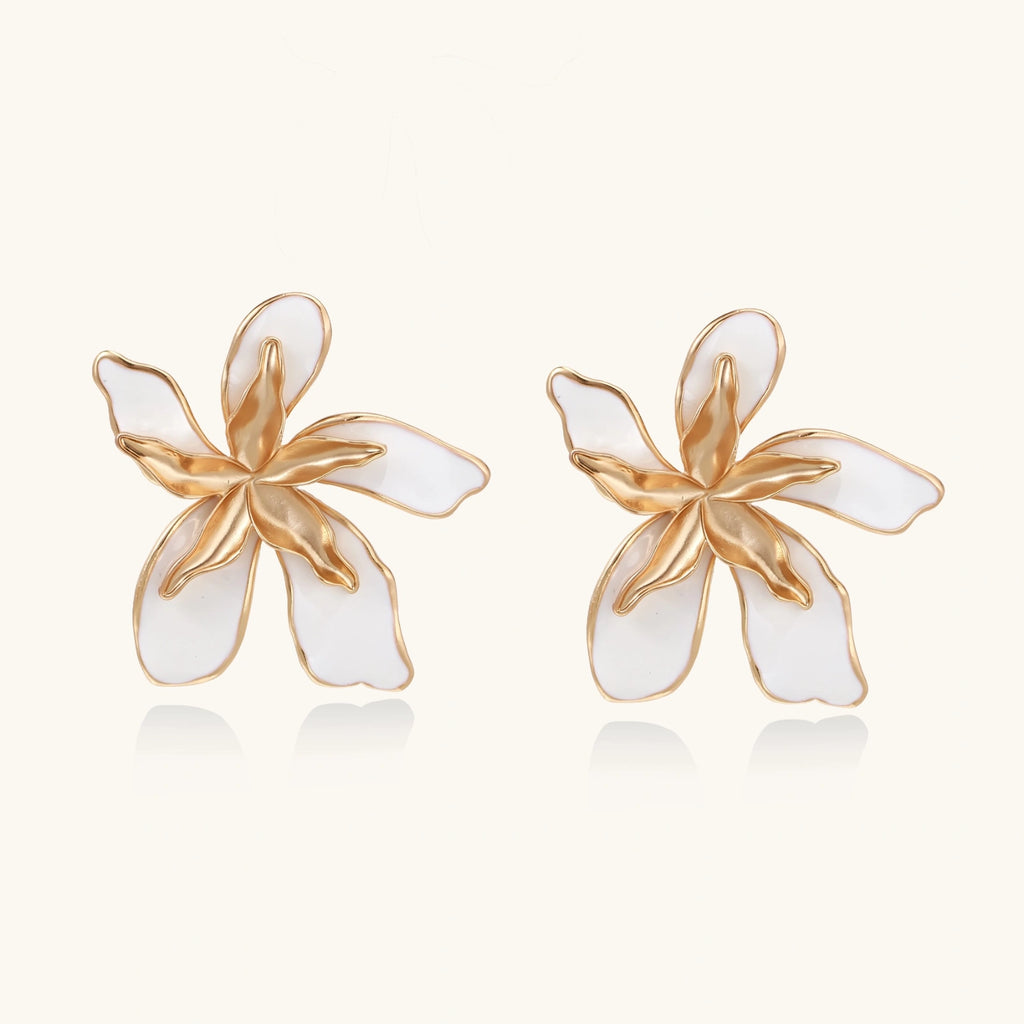 White enamel tropical flower earrings with sculptural gold-plated center and organic petal design on cream background