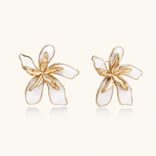 White enamel tropical flower earrings with sculptural gold-plated center and organic petal design on cream background