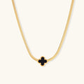 Dainty 18K gold-plated herringbone chain necklace with black enamel quatrefoil clover pendant on white background