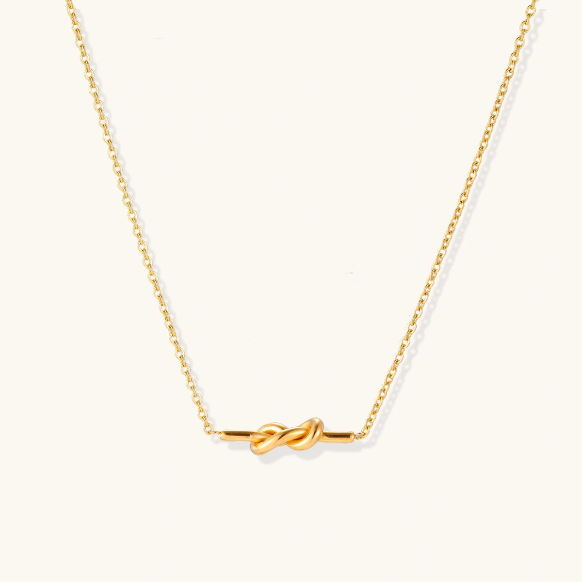 Dainty 18K gold plated necklace with infinity knot pendant on delicate chain against white background