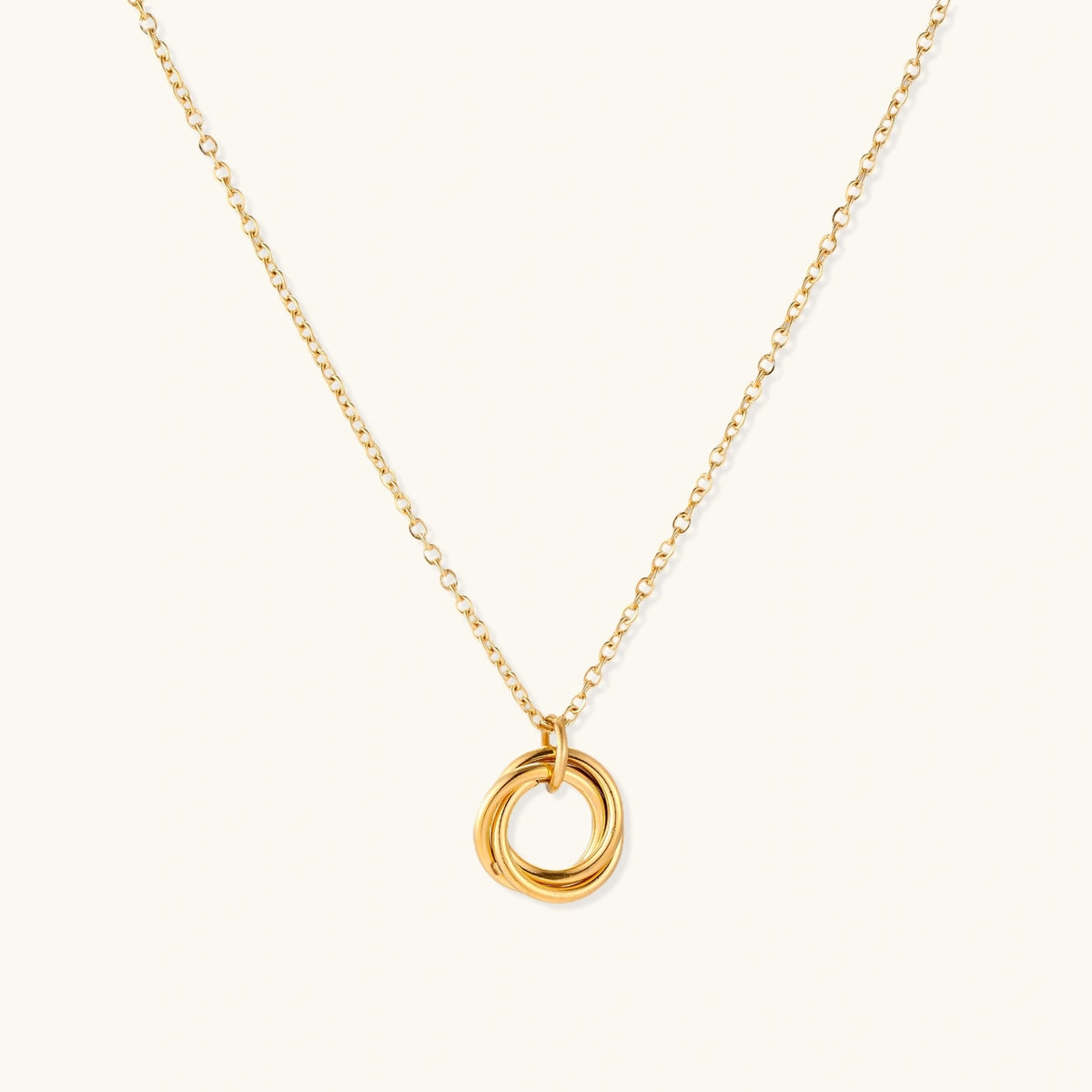 Delicate gold-plated necklace with three interlocking circle rings forming a minimalist knot pendant on cream background