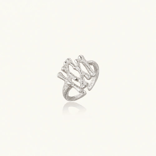 Sculptural sterling silver ring with organic branch design and textured surfaces on cream background