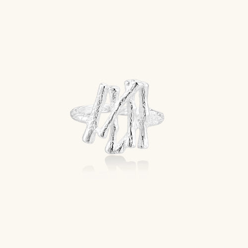 Sculptural sterling silver ring with organic branch design and textured surfaces on cream background