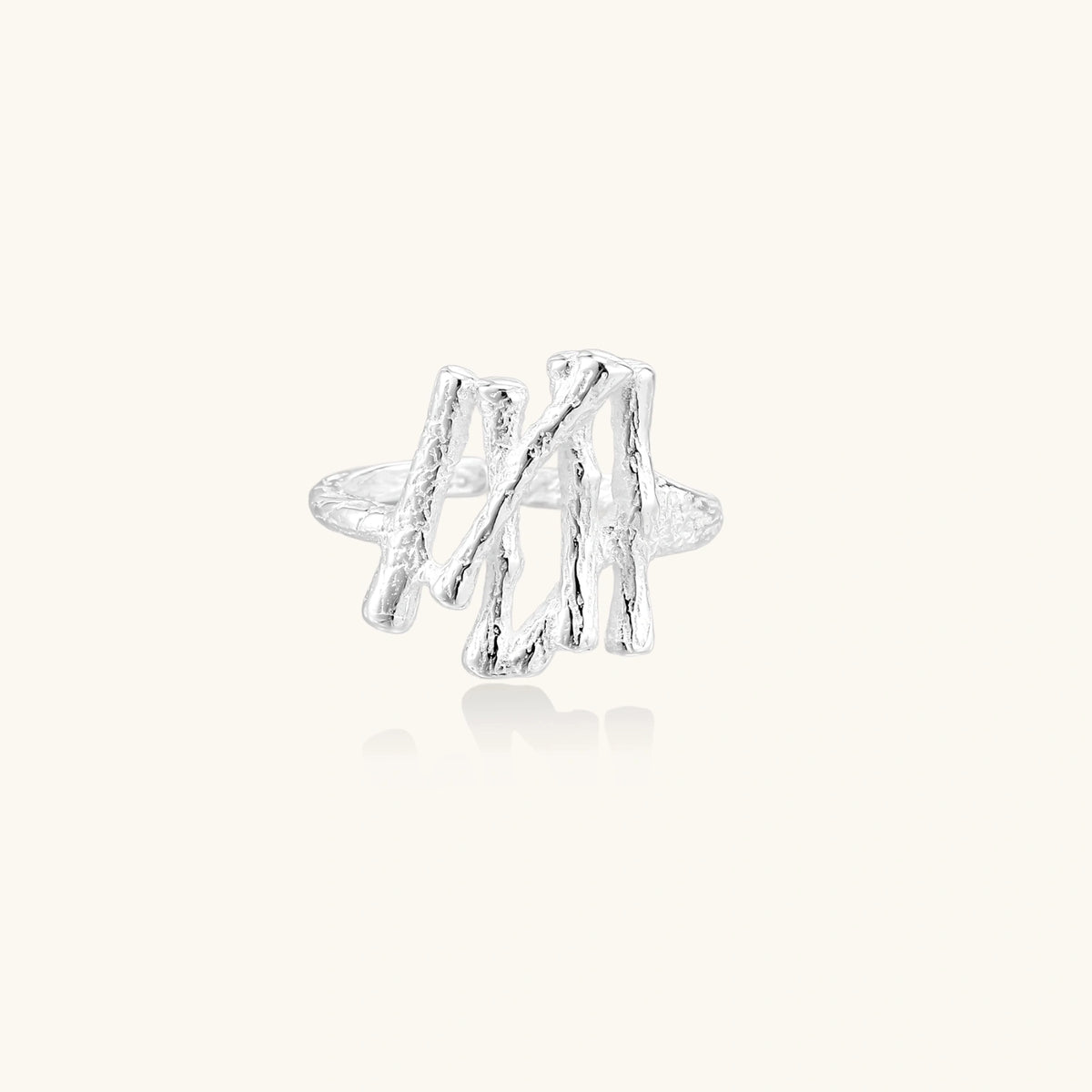 Sculptural sterling silver ring with organic branch design and textured surfaces on cream background