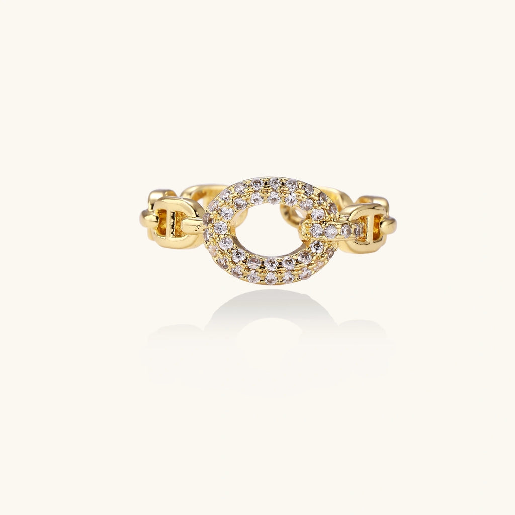 Gold-plated brass chain link ring with one oval CZ-pavé segment on cream background, adjustable cuff style.