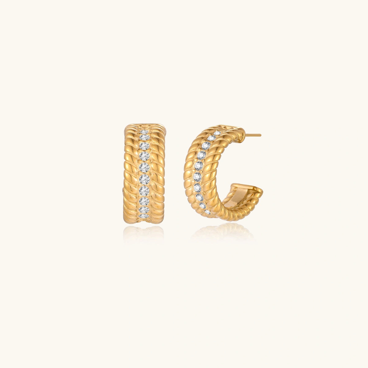 Textured gold huggie hoop earrings with raised ribbed rows creating dimensional sculptural design on cream background